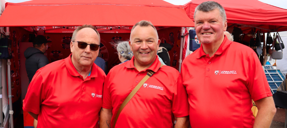 Three men in red tops stood outside in front of a red gazebo