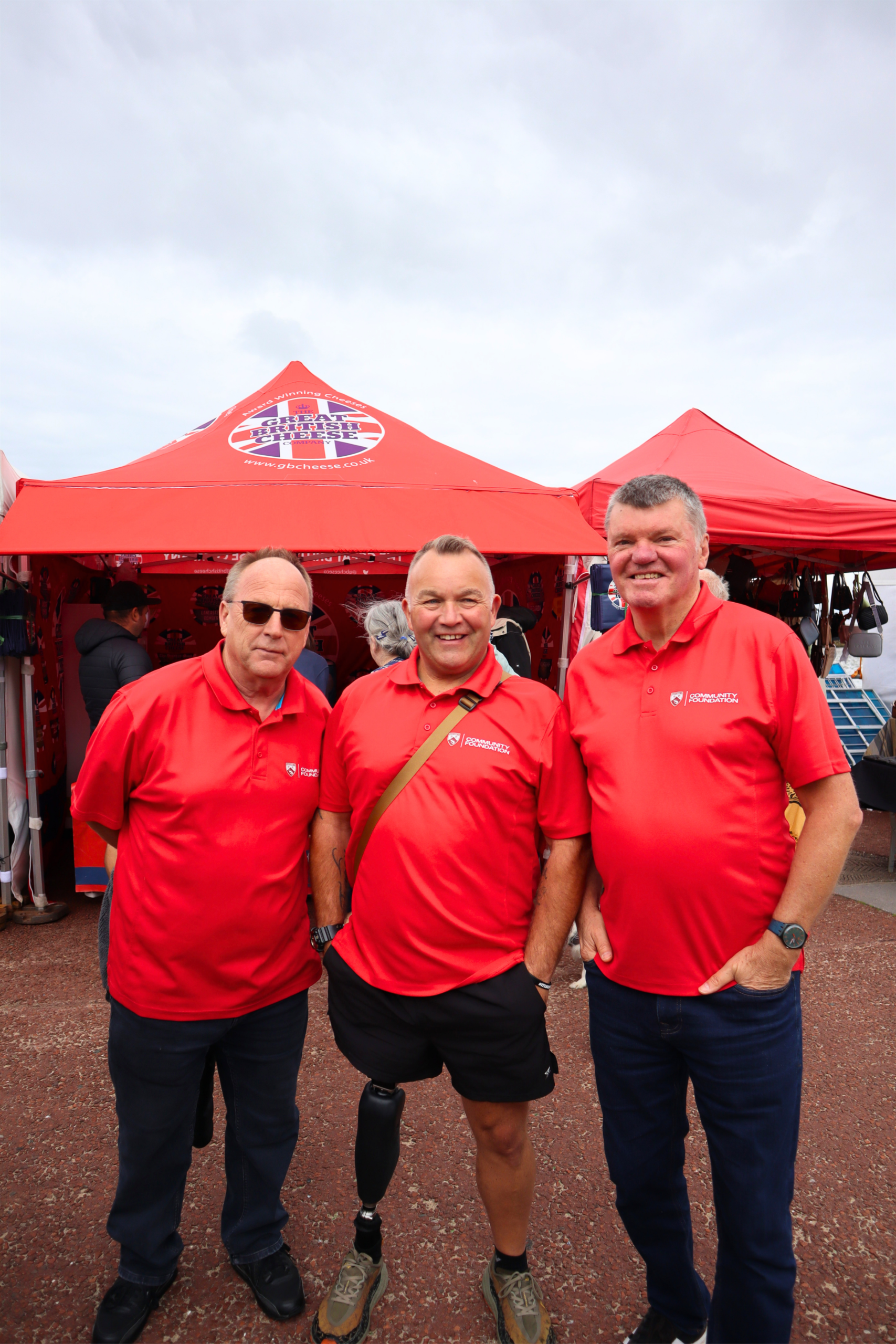Three men in red tops stood outside in front of a red gazebo