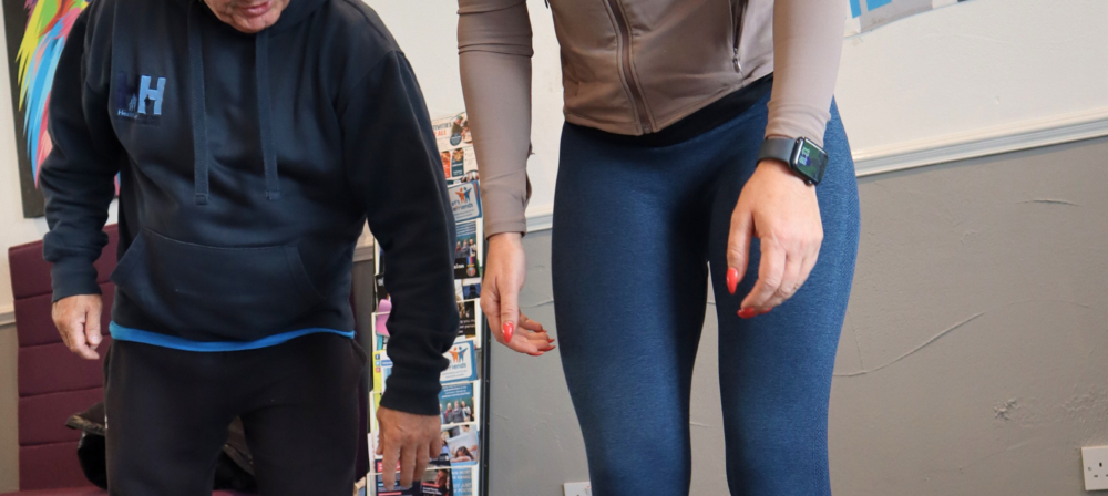 Coach and woman standing beside a barbell