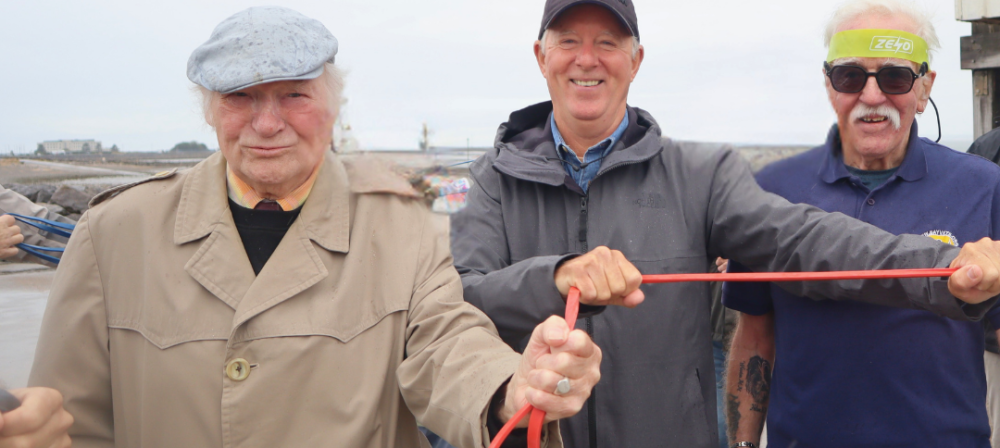 Group holding a rope by the shore
