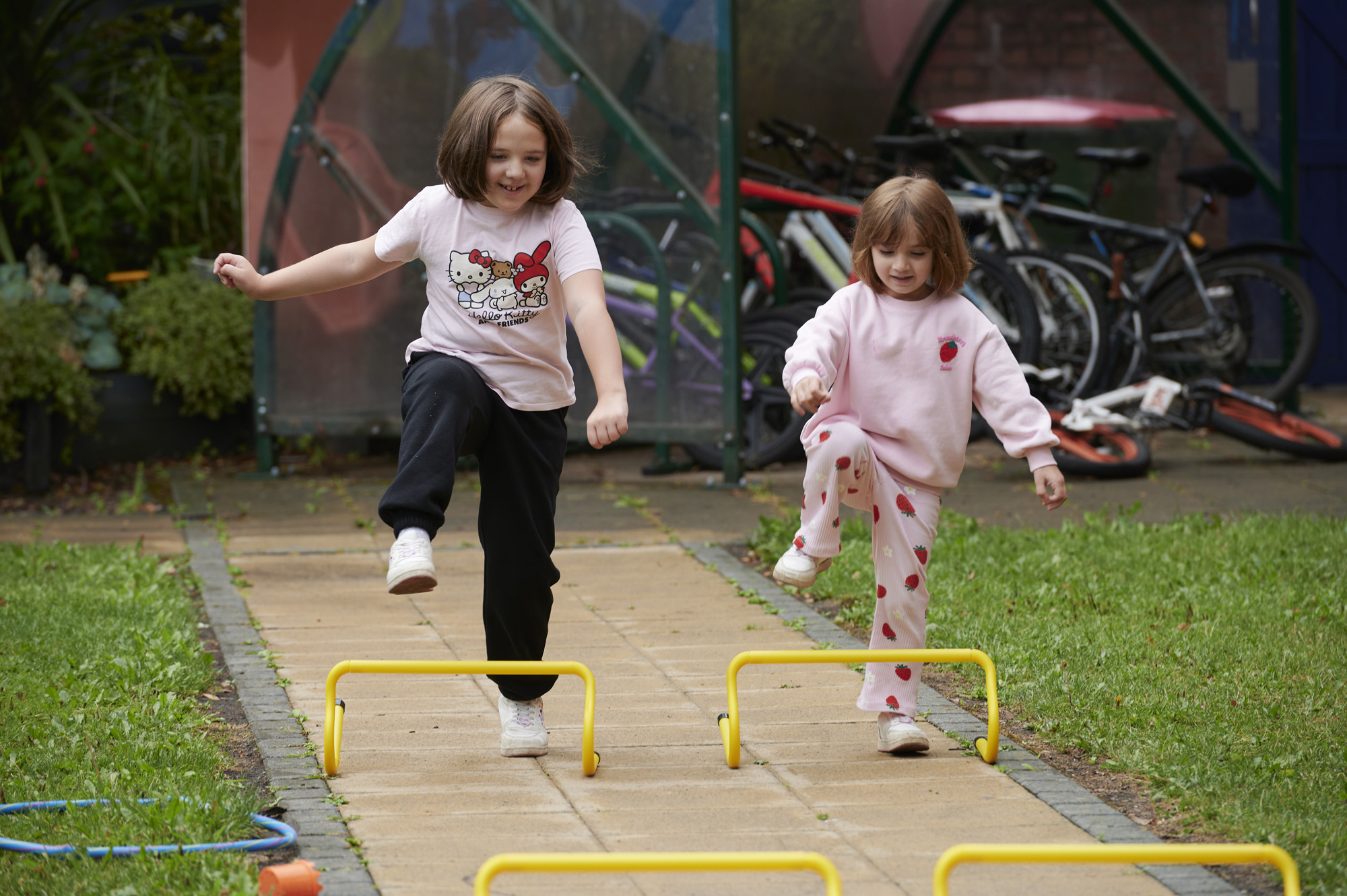 Two happy young girls playing with mini-hurdles outside