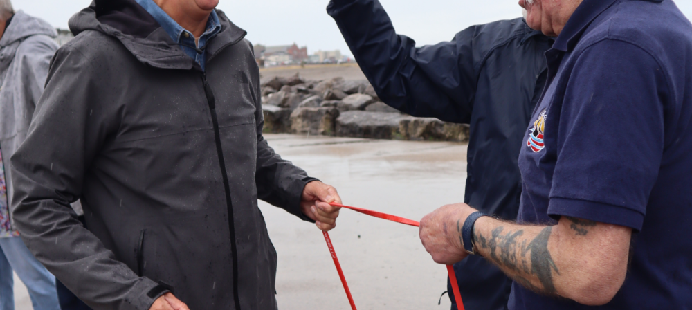 Two men holding a rope by the shore
