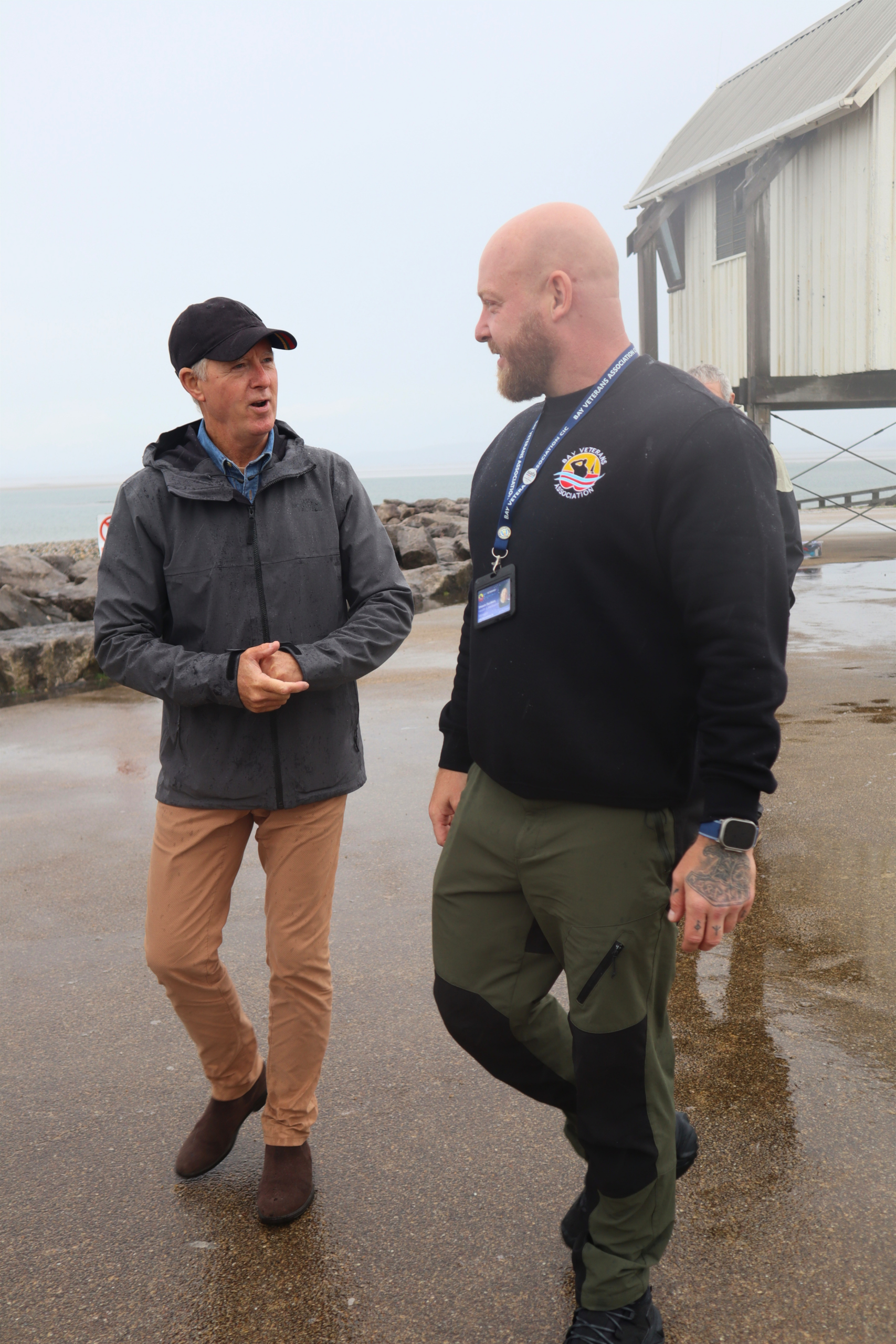 Two men walking beside a seaside building