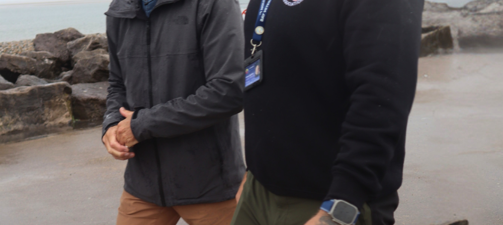 Two men walking together by the shore