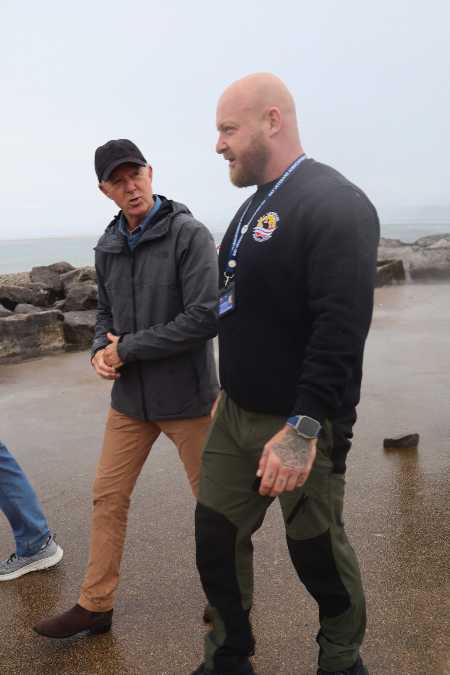 Two men walking together by the shore