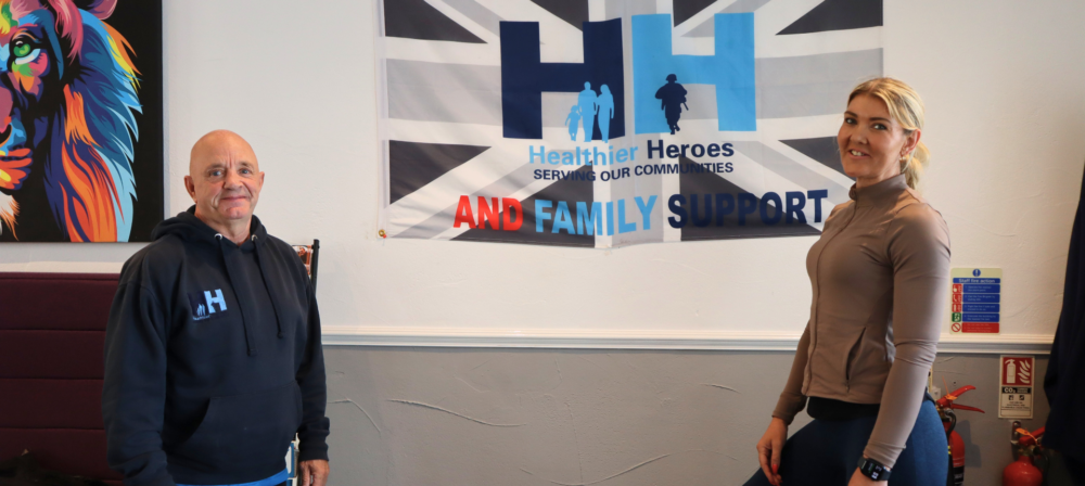 Two people posing beneath a veteran support sign