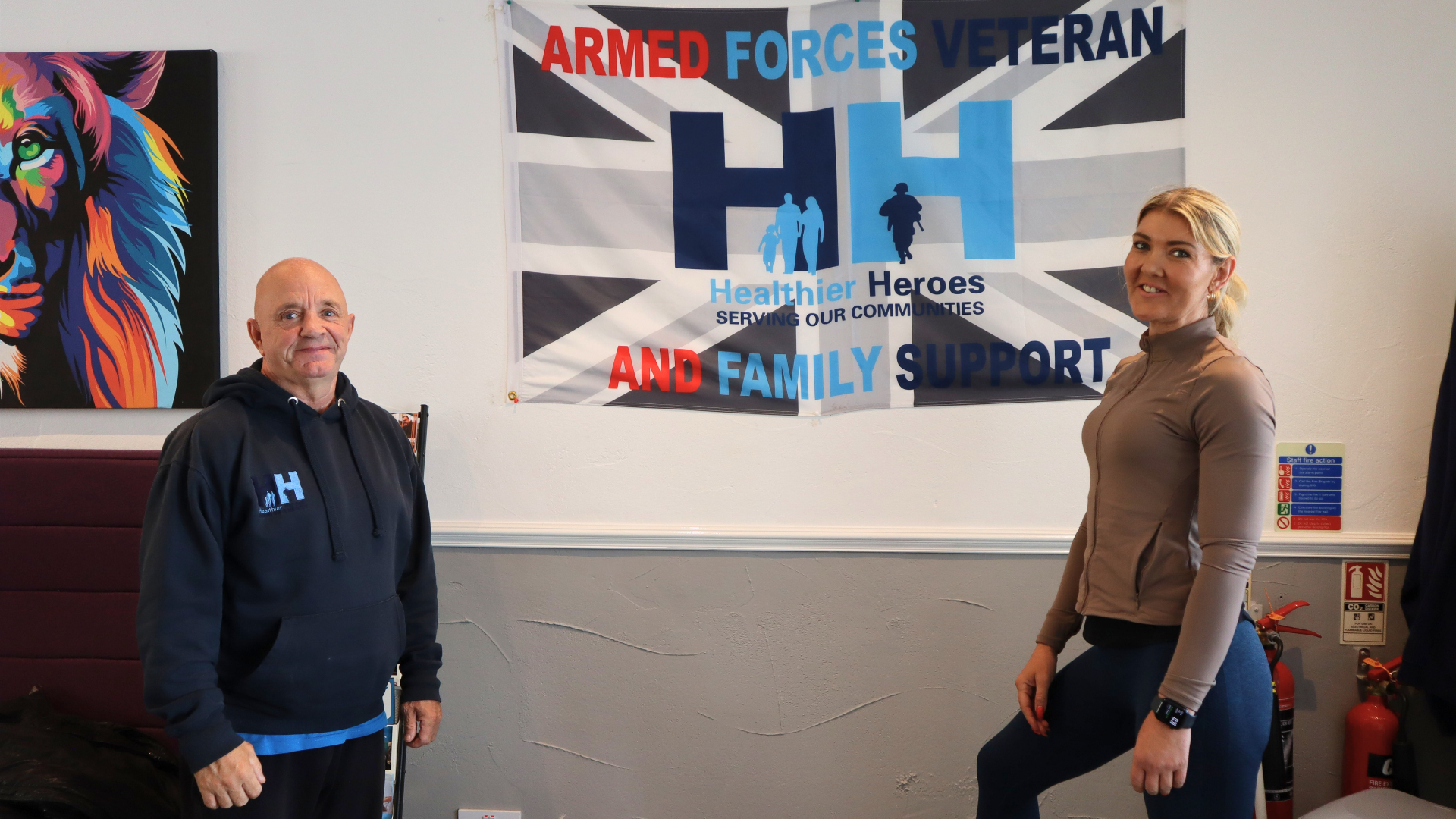 Two people posing beneath a veteran support sign