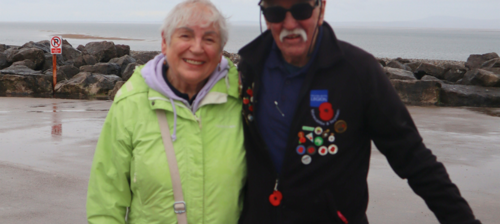 Two people standing by a rocky shoreline