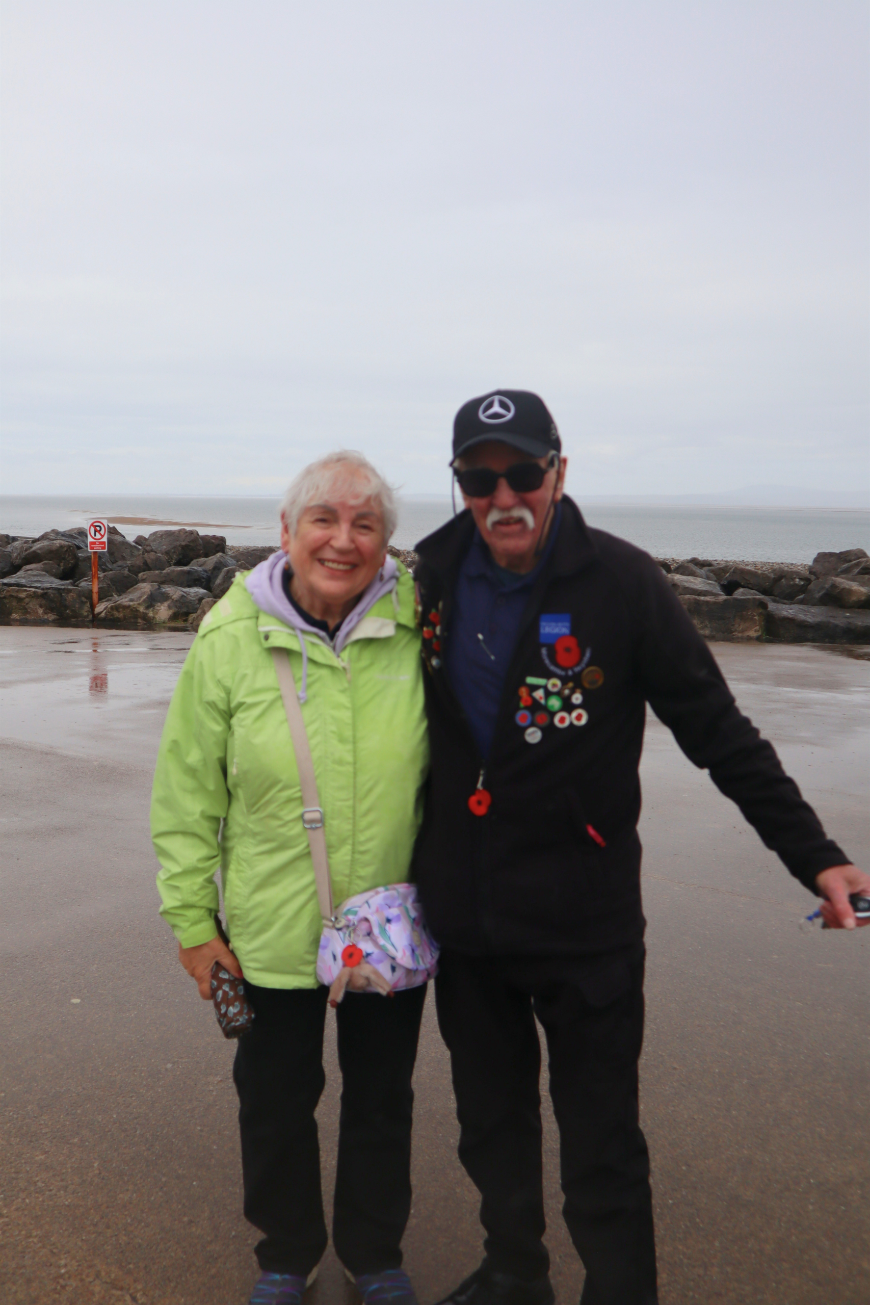 Two people standing by a rocky shoreline