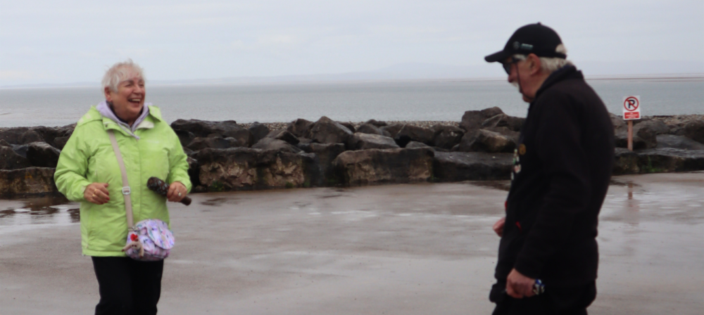Two people walking along a wet shoreline
