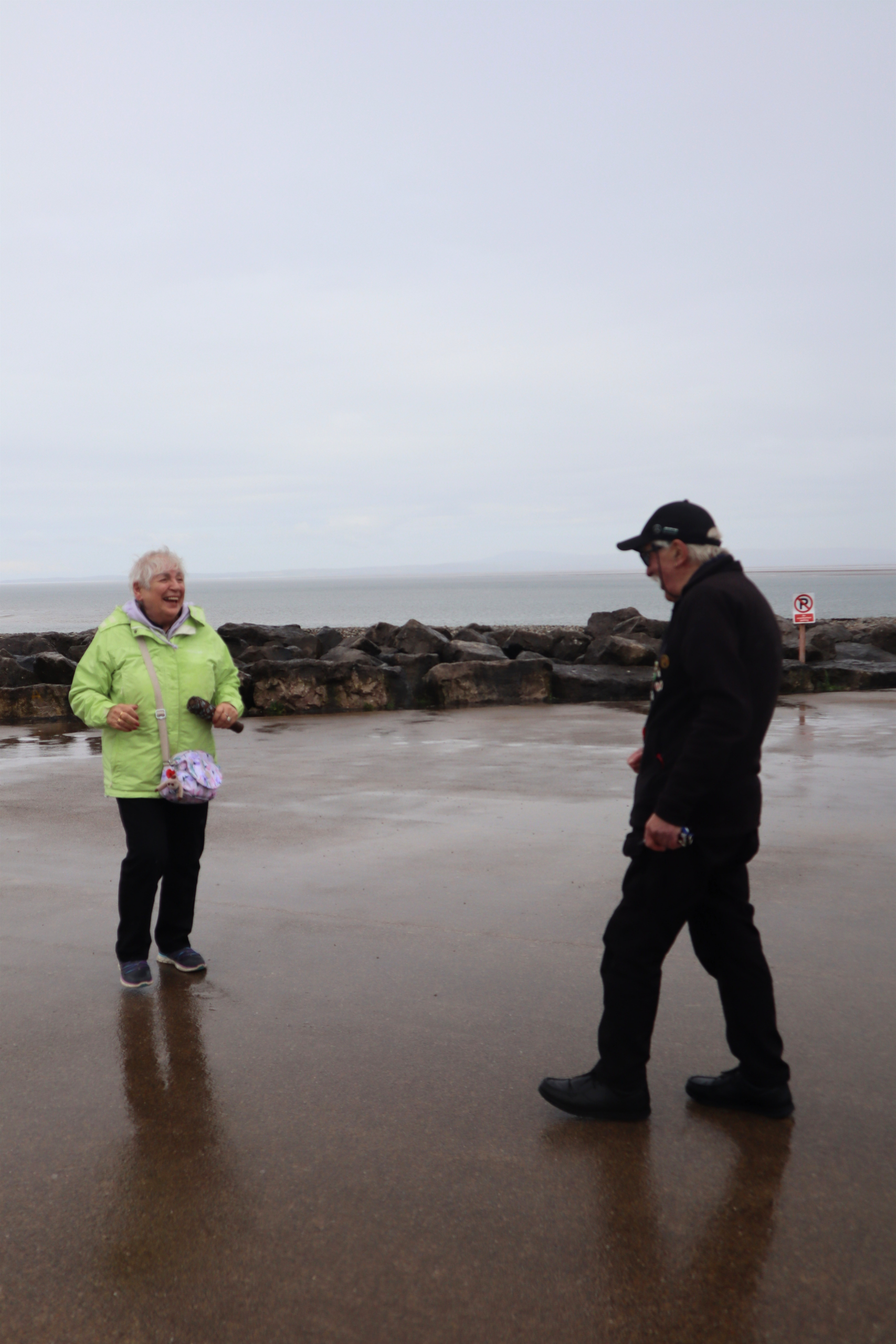 Two people walking along a wet shoreline