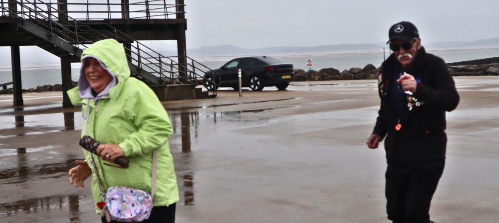Two people walking beside a seaside pier