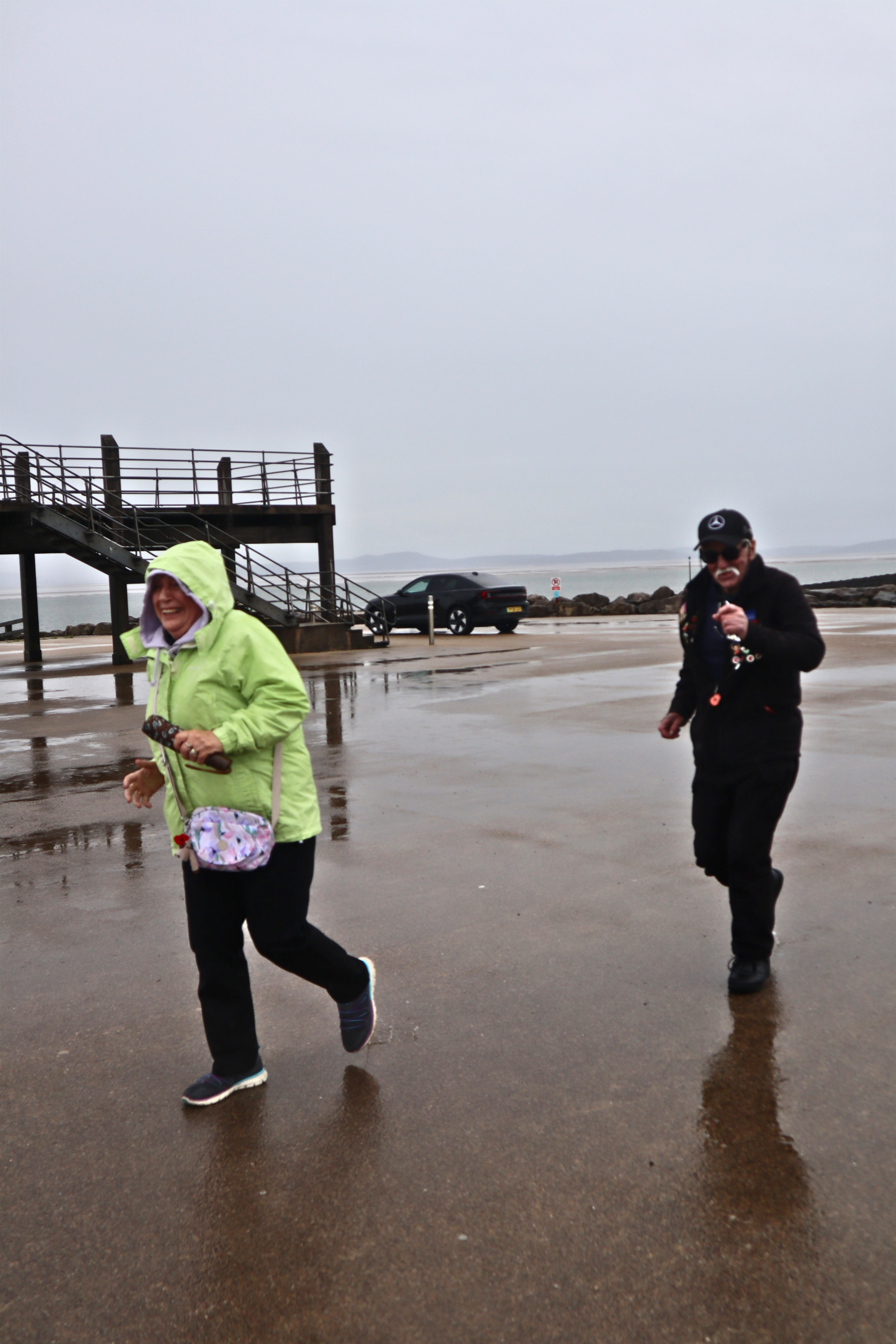 Two people walking beside a seaside pier