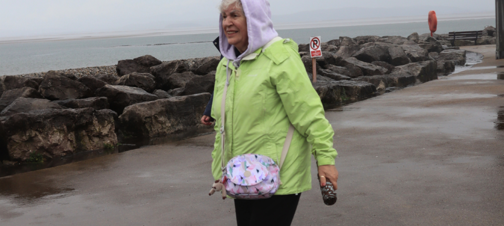 Woman in a green jacket walking by the shore