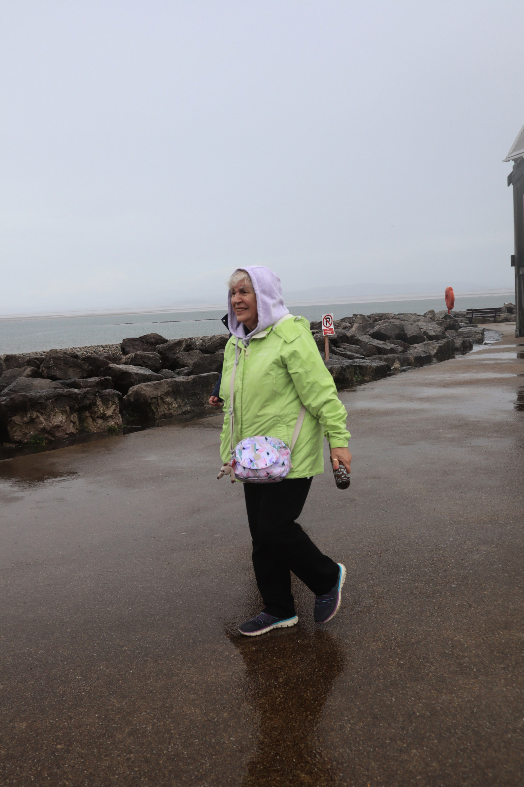 Woman in a green jacket walking by the shore