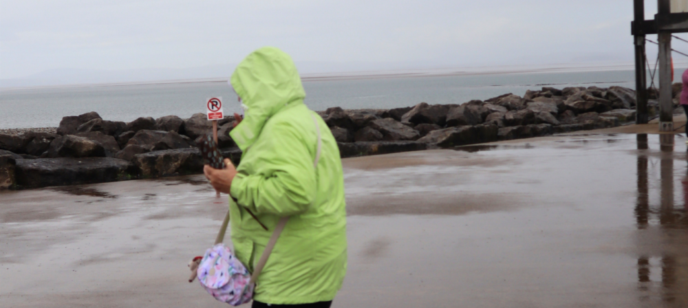 Woman in a green jacket walking on the beach