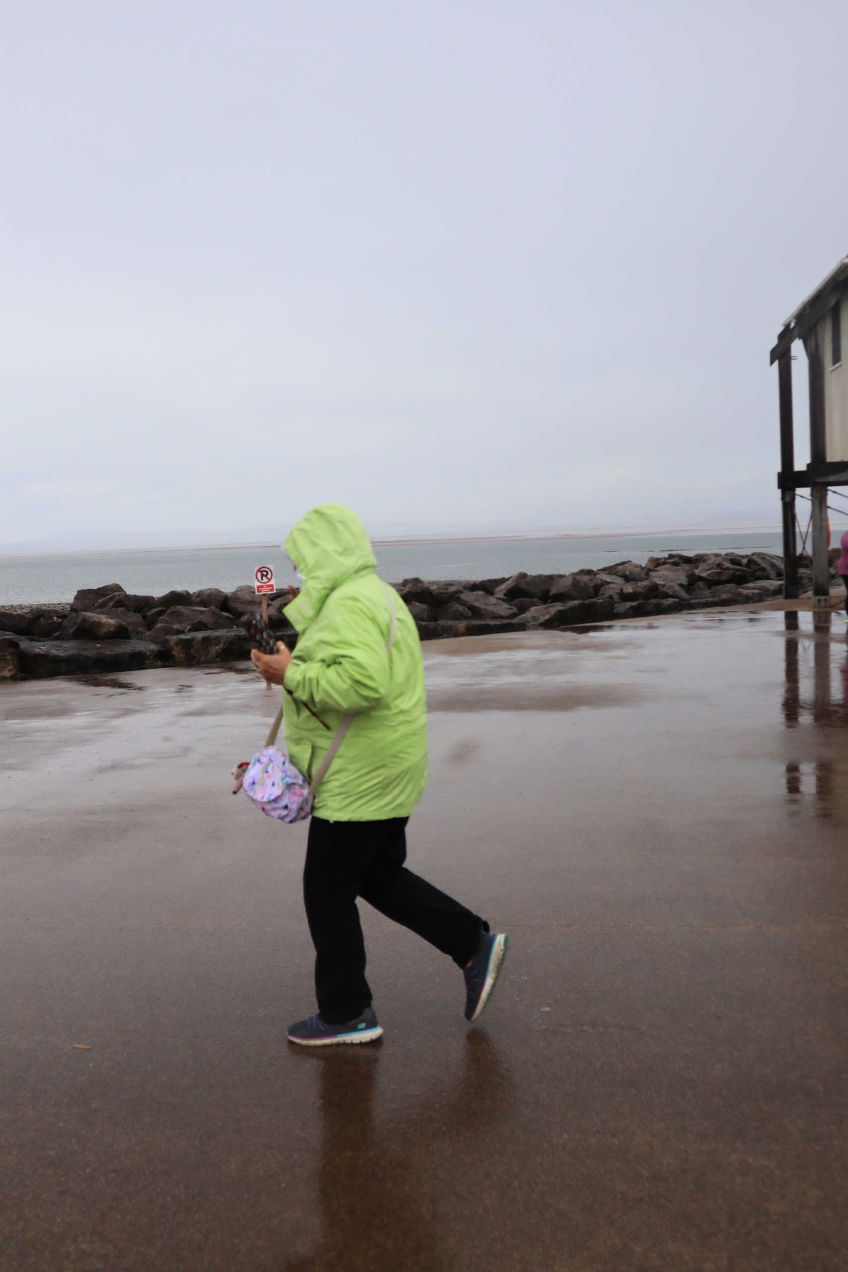 Woman in a green jacket walking on the beach