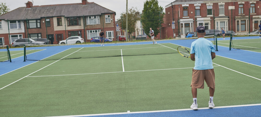 Male standing on tennis court at Moor Park