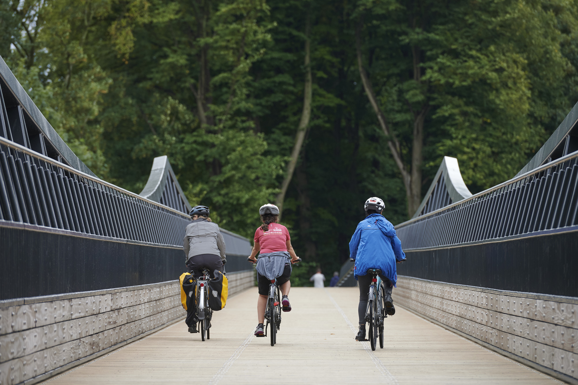 Three cyclists riding away from camera across Tram Bridge