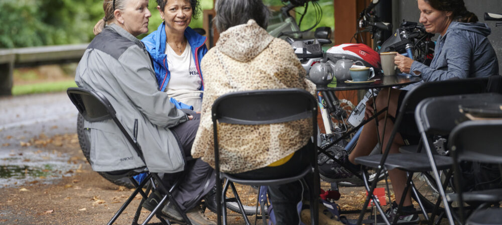Three ladies sitting talking whilst taking a break on a guided cycle ride from Preston Train Station to Avenham Park, Preston, Lancashire, UK.