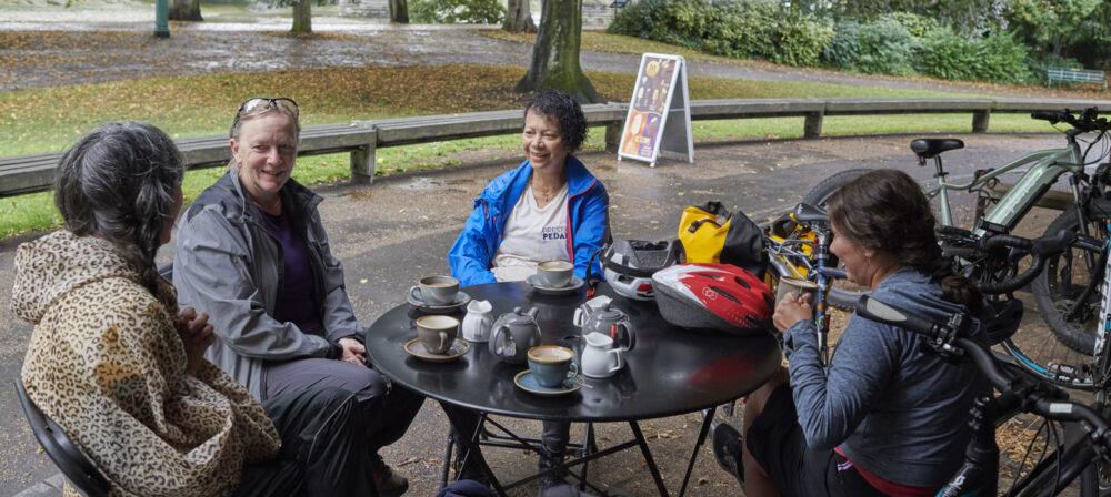 Group of people sitting whilst taking a break on Preston Pedals on a guided cycle ride from Preston Train Station to Avenham Park, Preston, Lancashire, UK.