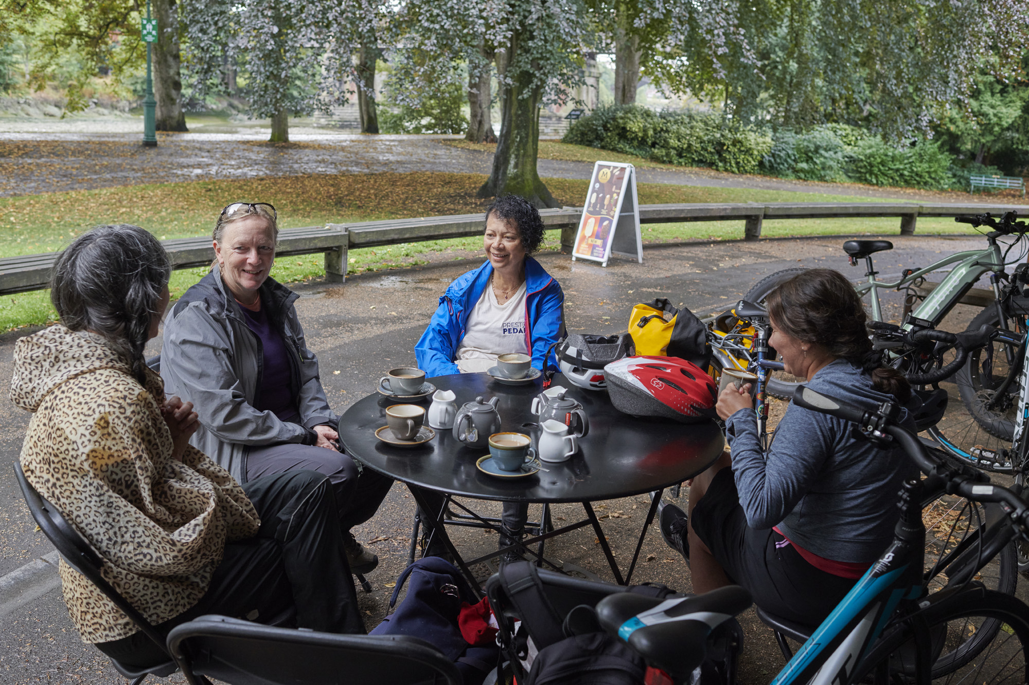 Group of people sitting whilst taking a break on Preston Pedals on a guided cycle ride from Preston Train Station to Avenham Park, Preston, Lancashire, UK.