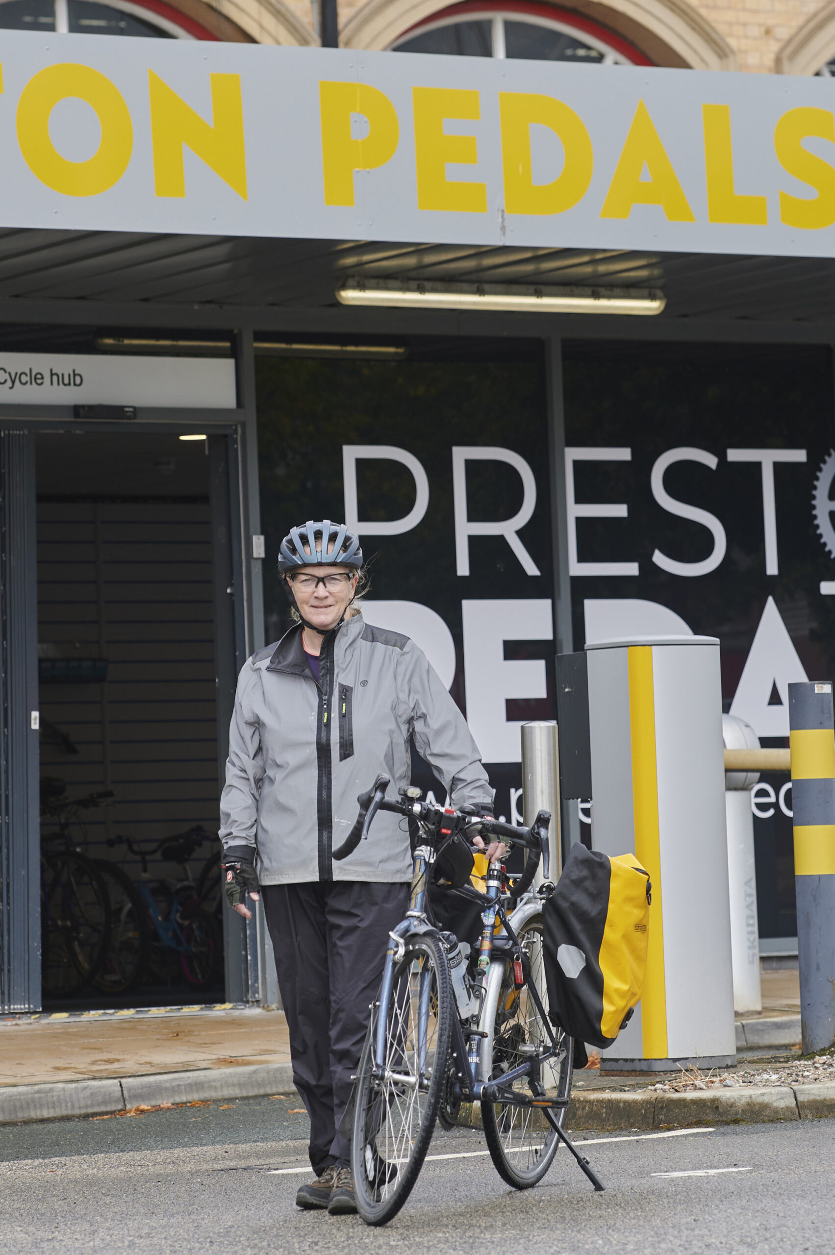 Cyclist, wearing helmet, standing with bike outside Preston Pedals