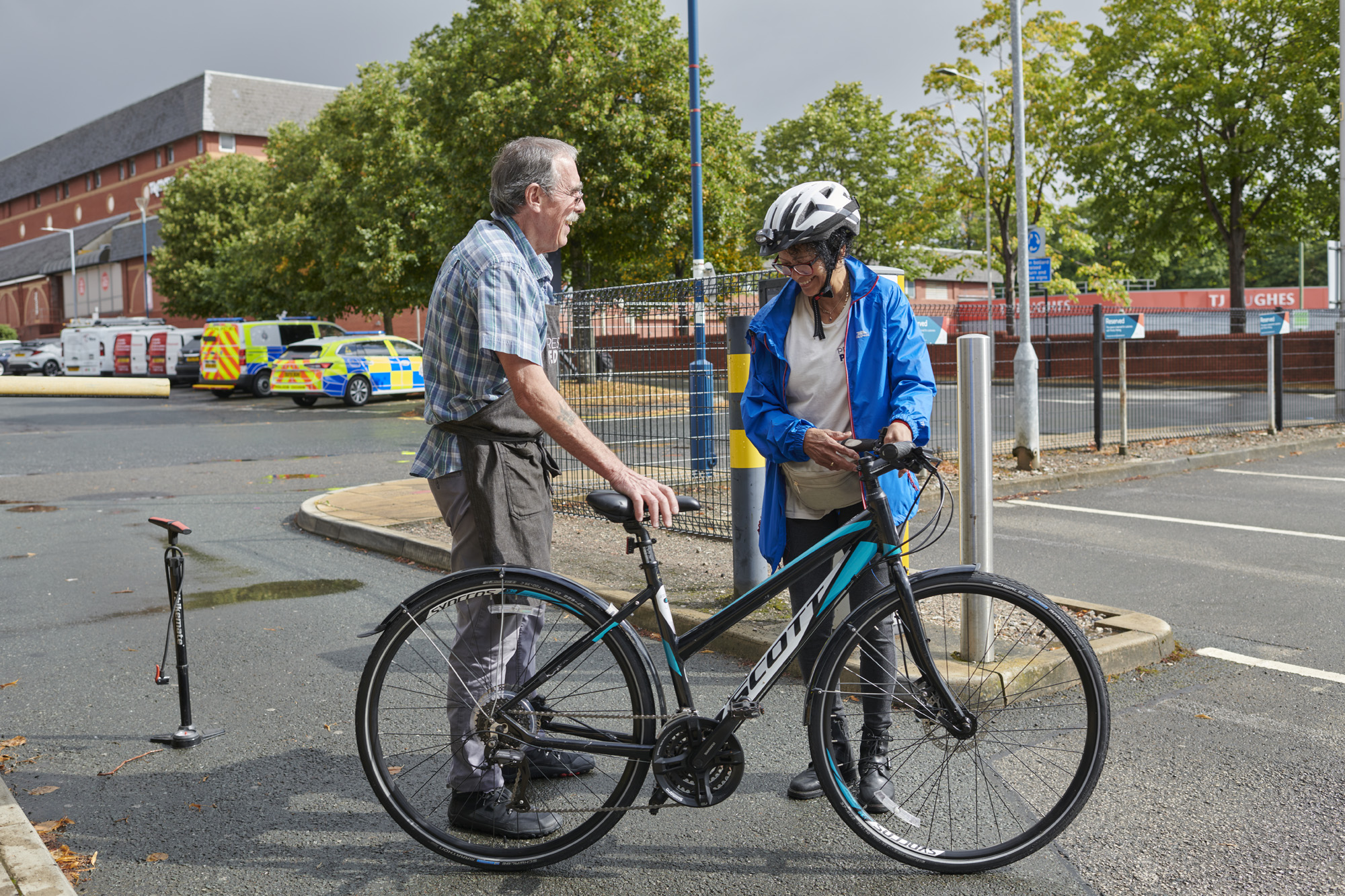 Male talking to male cyclist wearing helmet and holding handlebars of bike