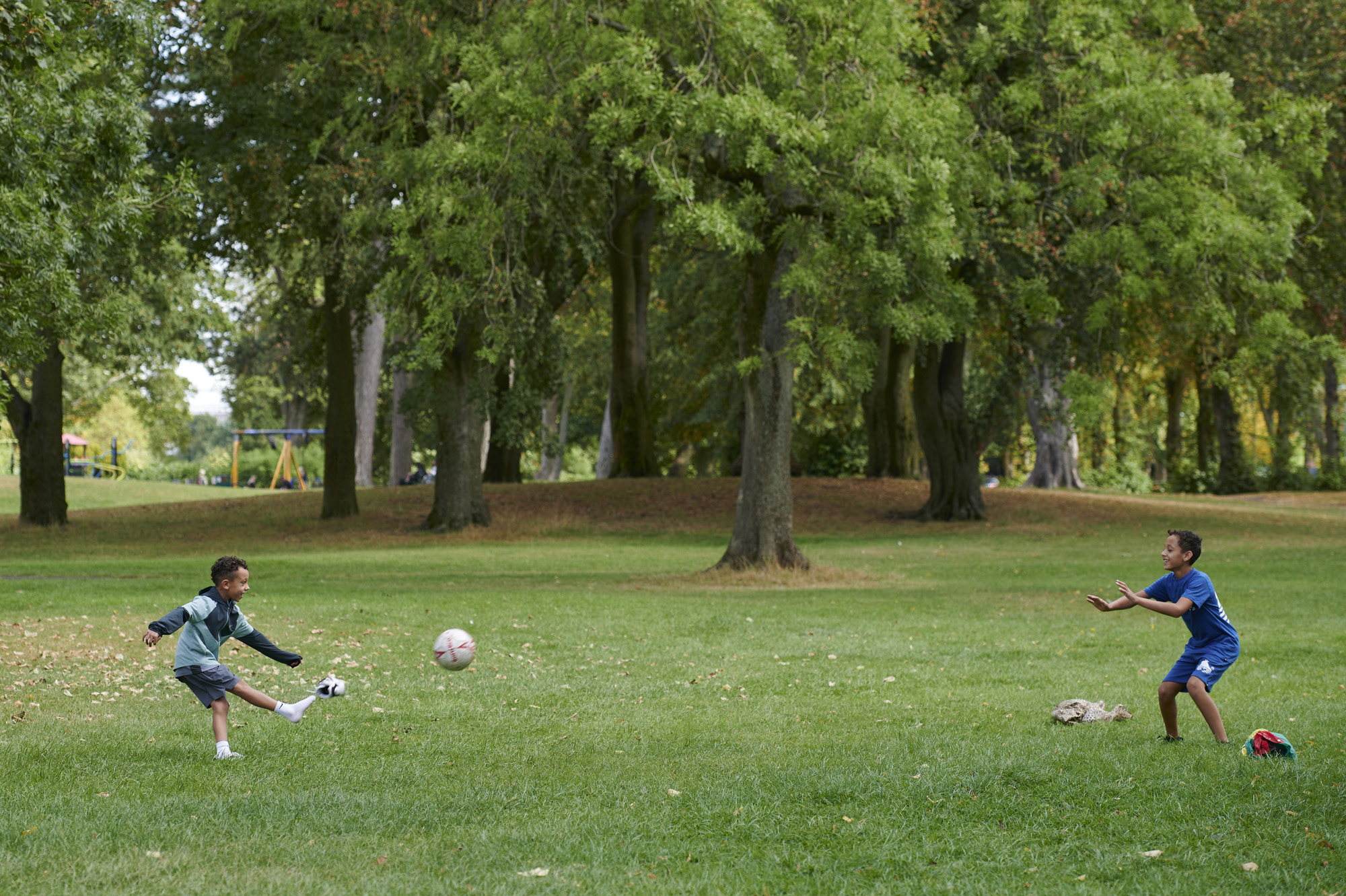 Two young brothers playing football together in Moor Park