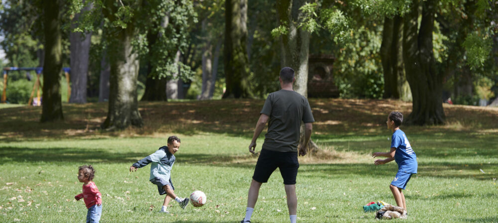 Father, two brothers and young sister playing with a ball in Moor Park