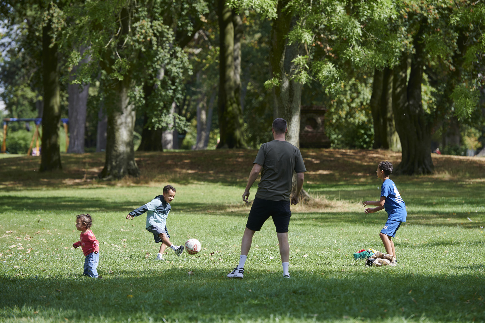 Father, two brothers and young sister playing with a ball in Moor Park