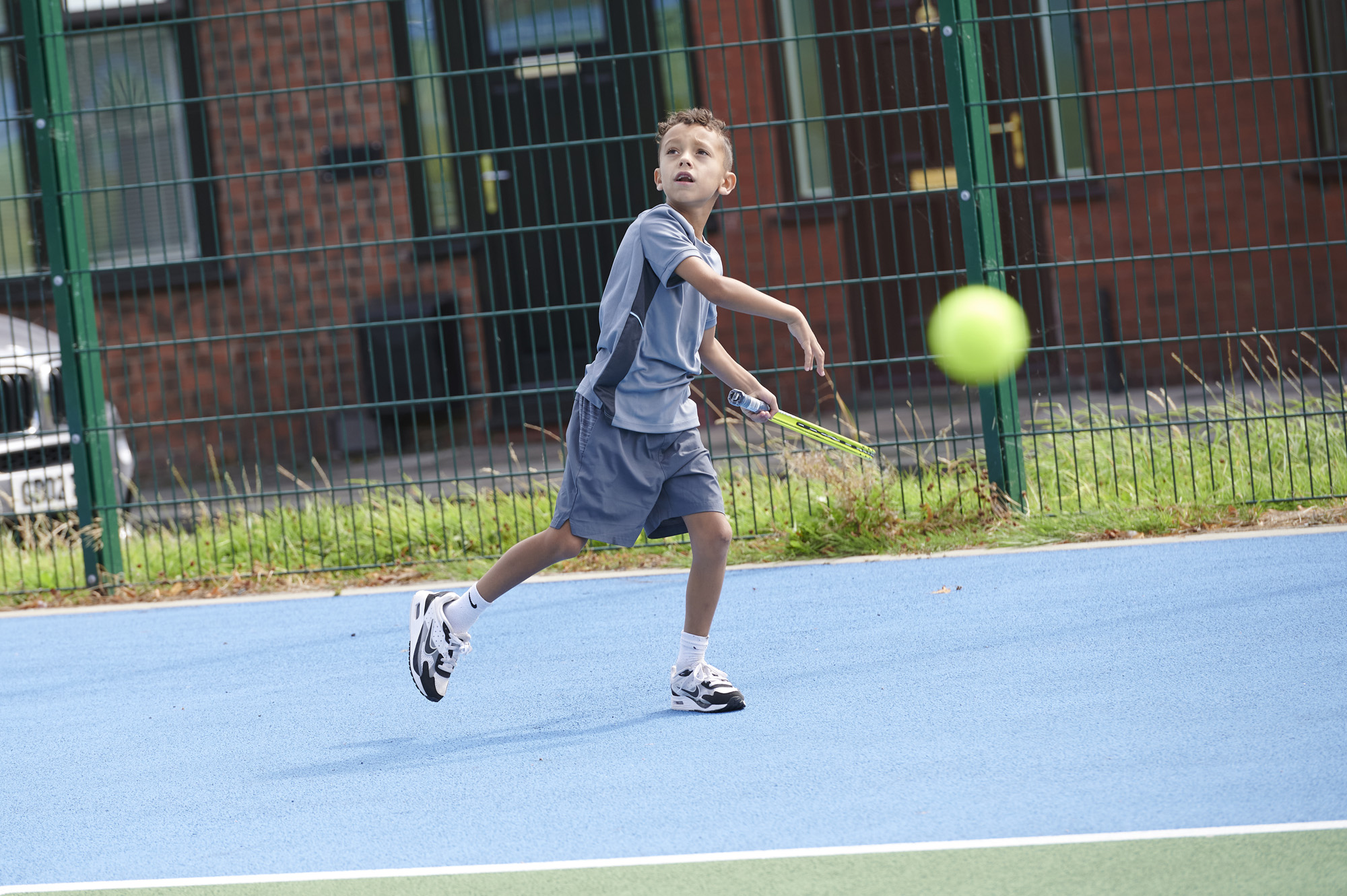 Young boy with tennis racket and ball playing tennis in Moor Park