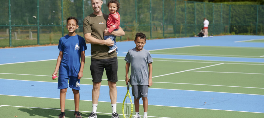 Father, two sons and daughter on tennis court at Moor Park