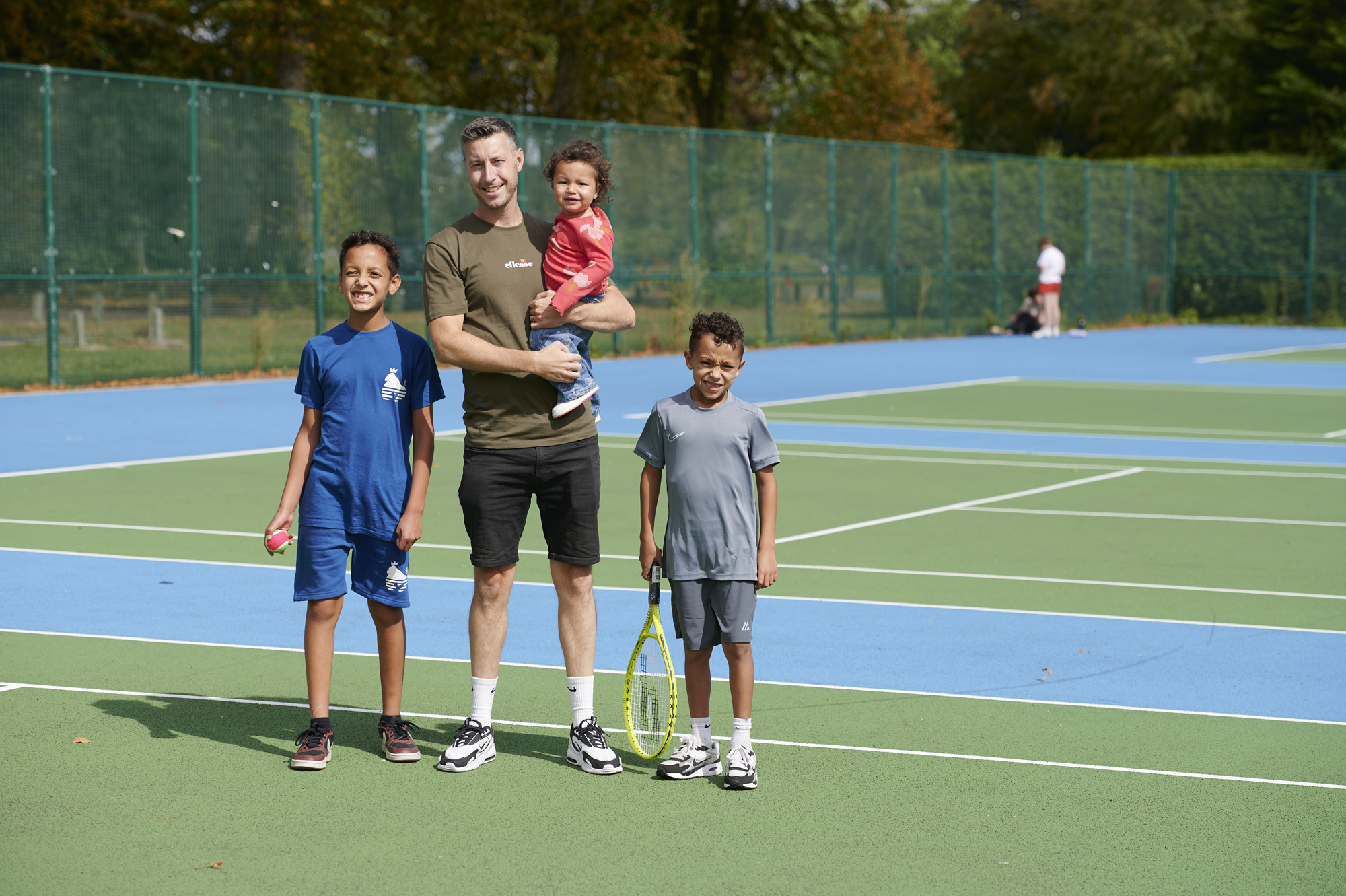 Father, two sons and daughter on tennis court at Moor Park