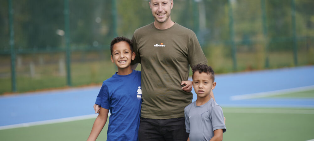 Father with two sons on tennis court in Moor Park