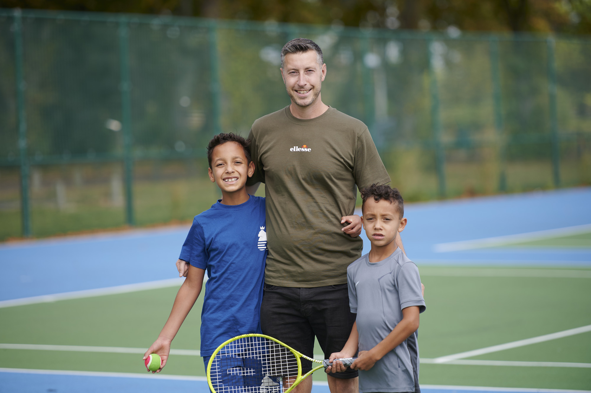 Father with two sons on tennis court in Moor Park