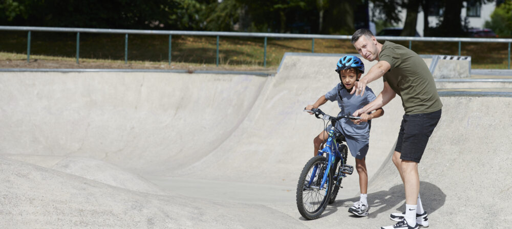 Adult male helping young male on bike