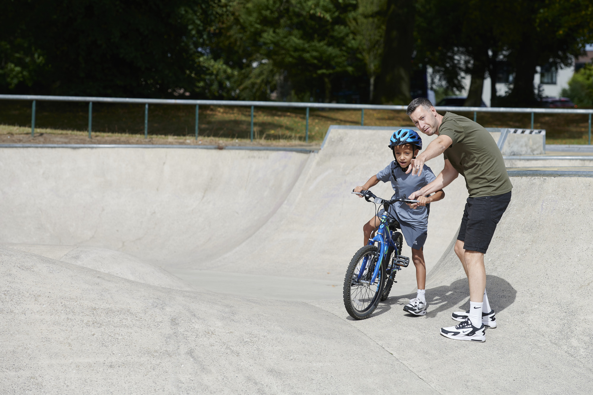 Adult male helping young male on bike